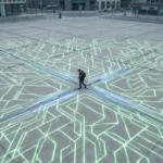Vue aérienne d'une personne marchant sur une place urbaine avec des motifs géométriques lumineux verts, symbolisant la productivité numérique fragmentée et les distractions digitales.